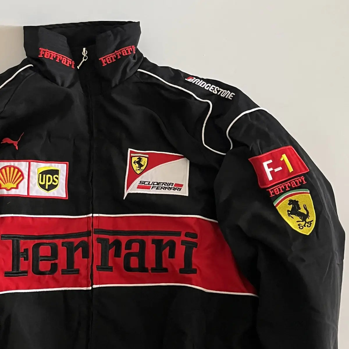 Black Ferrari jacket with various logos on a white background