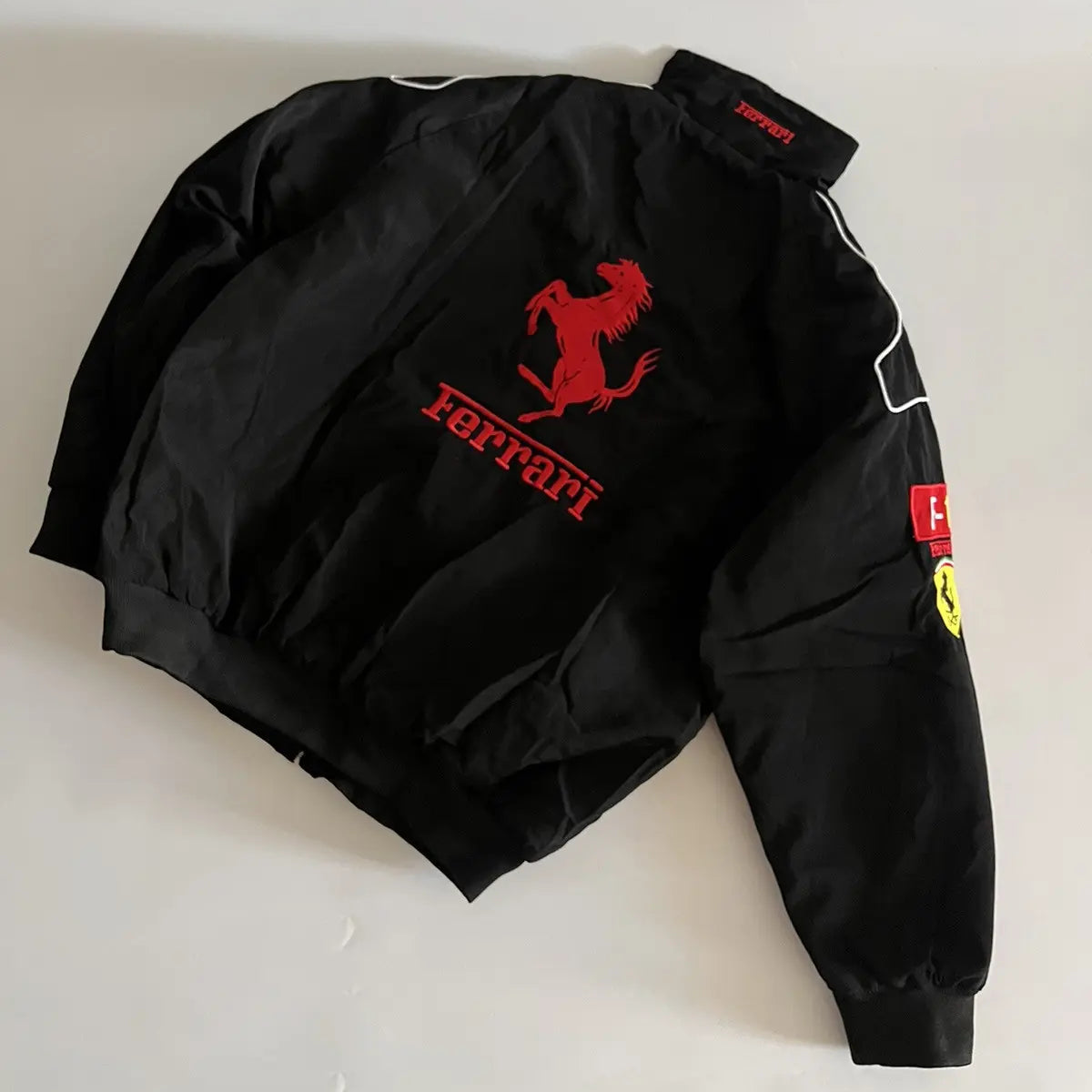 Black jacket with Ferrari logo on a light gray background